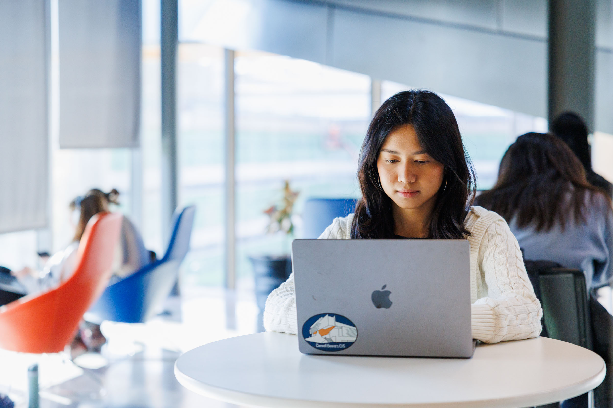 a young female students works on her laptop sitting at a table
