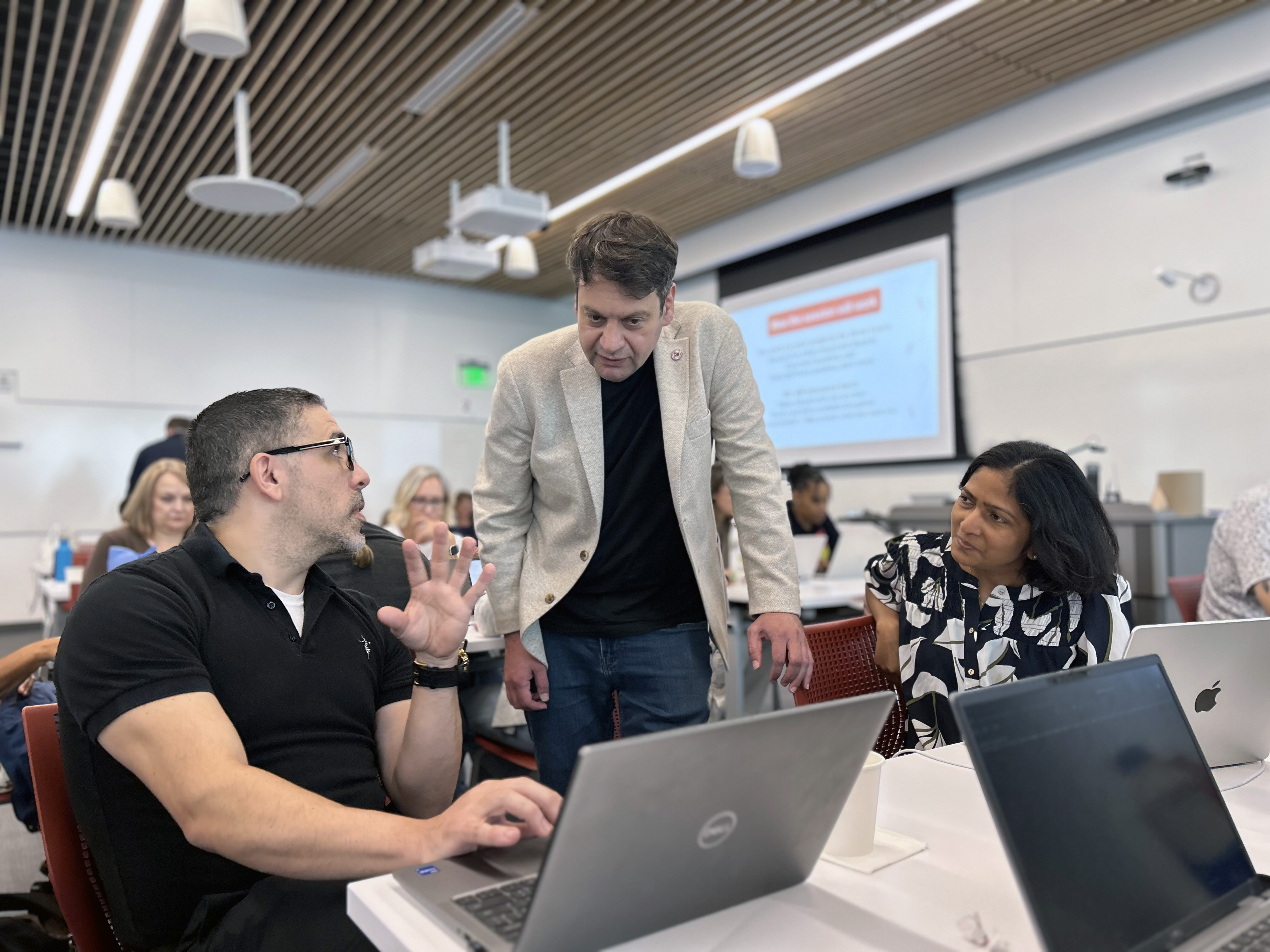 Sorin Lerner works alongside a male and female staff member at the We Do AI Bowers series