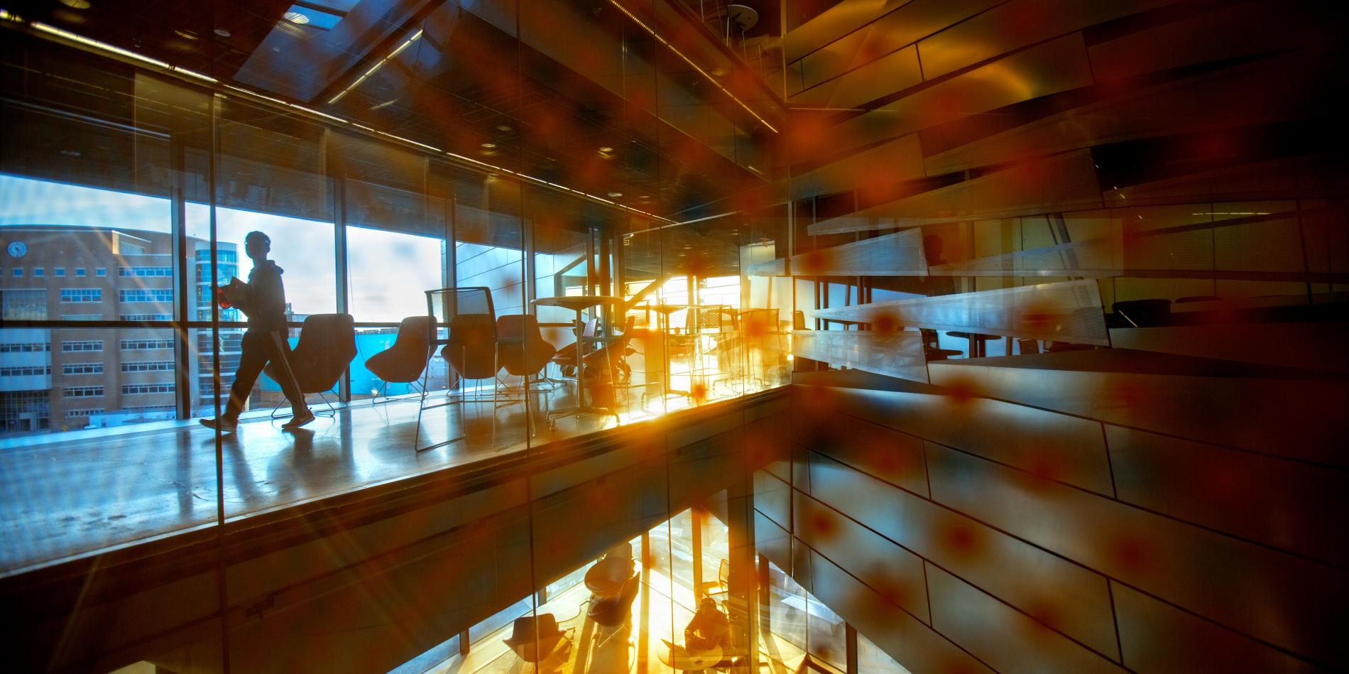 people walking along hallways, sun setting, reflected in glass