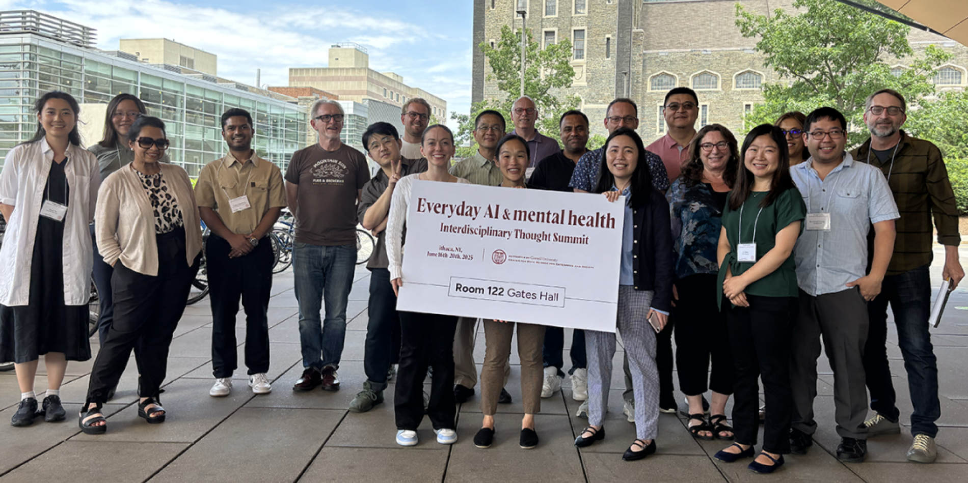 A color photo showing a group of people outside holding a large sign
