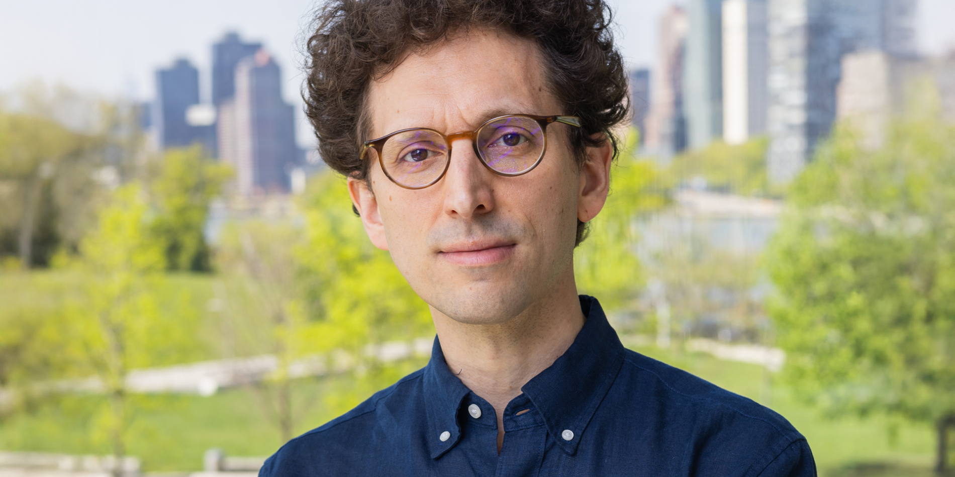 A color photo of Yoav Artzi infront of a city park background
