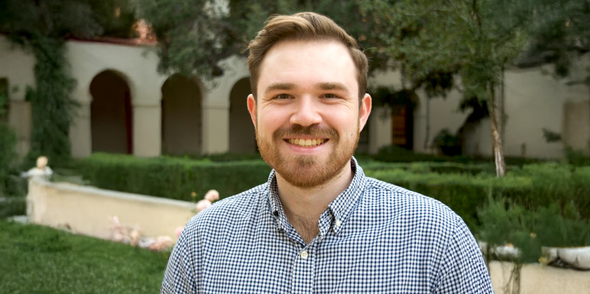 A color photo of a man standing outside.