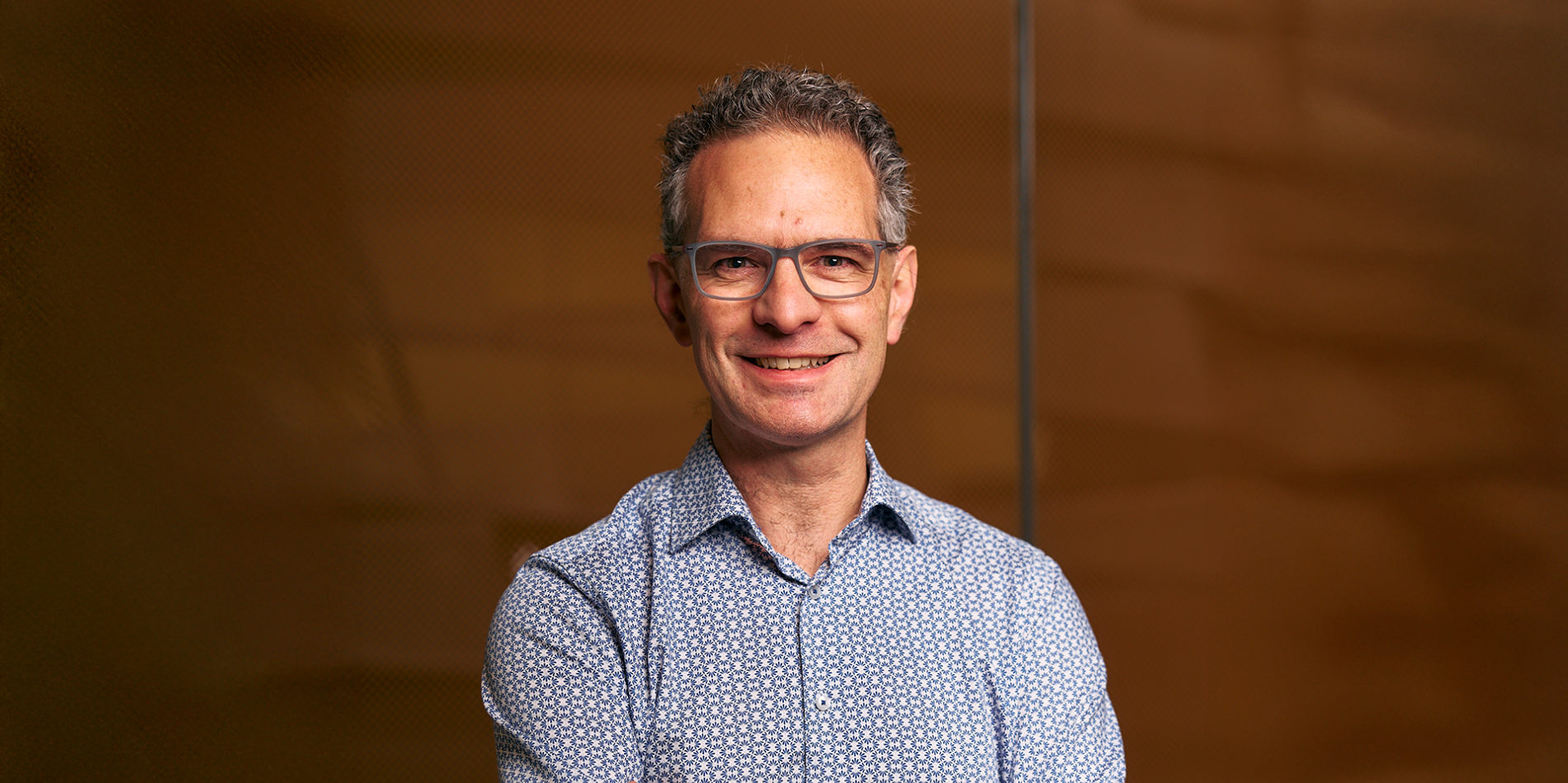 A photo of Stephen Marschner, a smiling man in front of a brown background