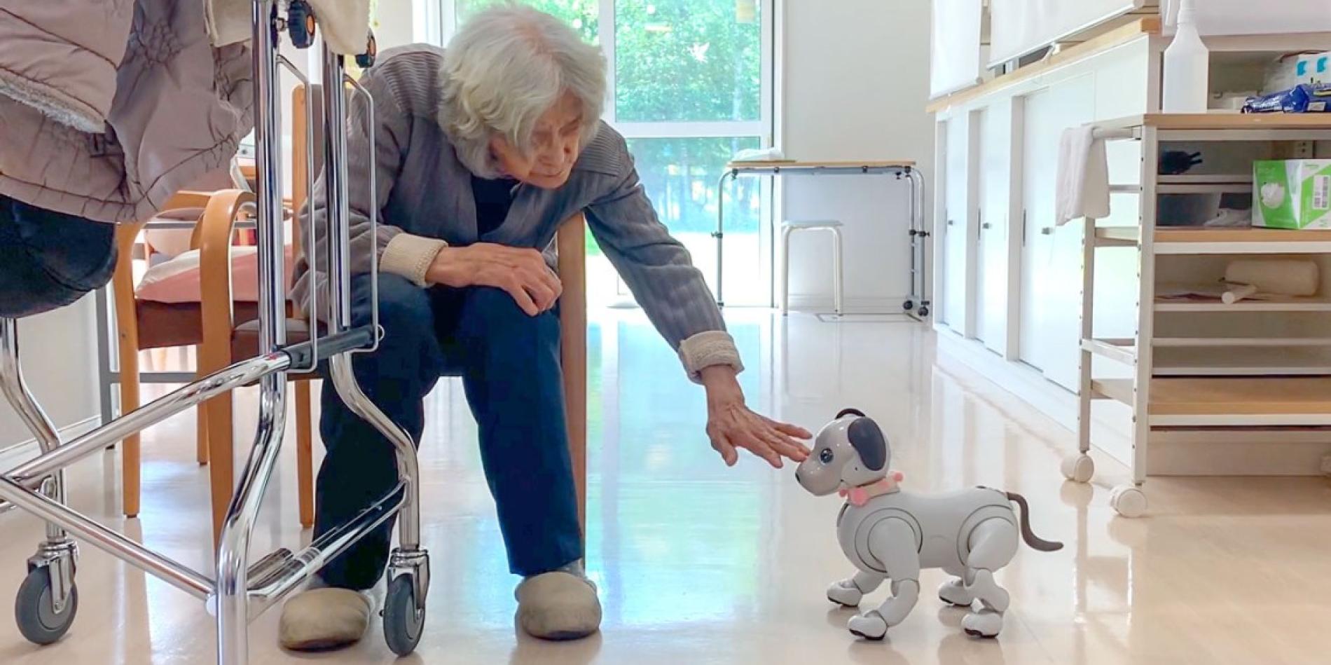 A woman greets a donated Sony aibo social robot at a senior care facility in Japan’s Hokkaido region.