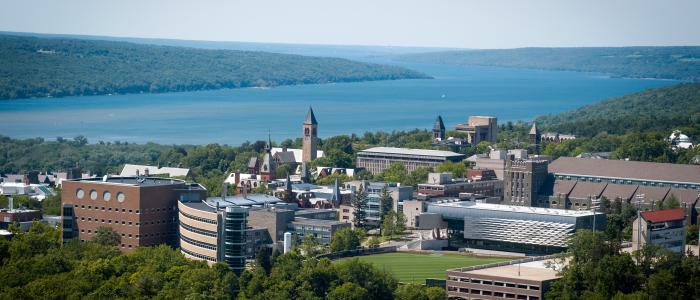 aerial view of cornell with buildings and a bright blue cayuga lake with green trees