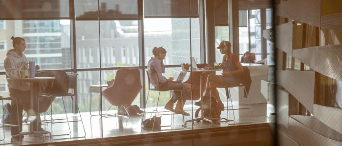 View through glass of people sitting at tables in Gates Hall