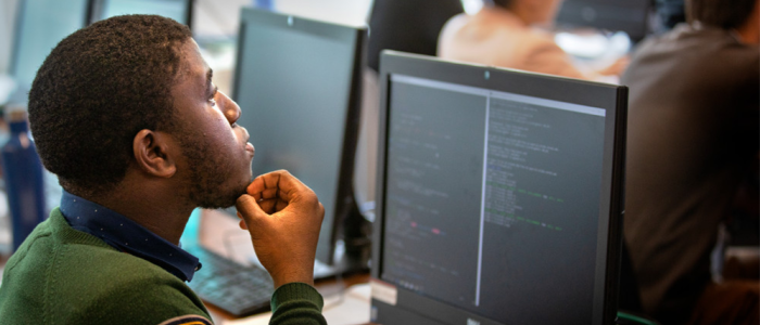 A student looks at code on a desktop computer screen in a classroom.