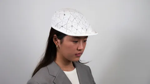 A color photo of a woman wearing a white cap.
