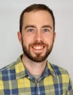 a man with short brown hair and a beard wearing a yellow and blue plaid shirt