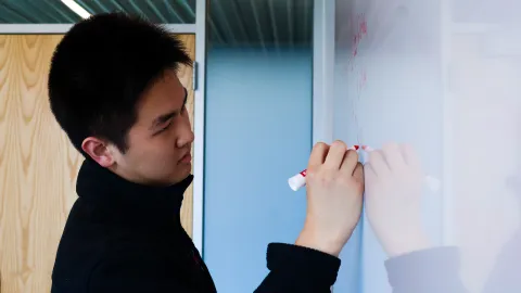 Andrew Kang writes on a white board