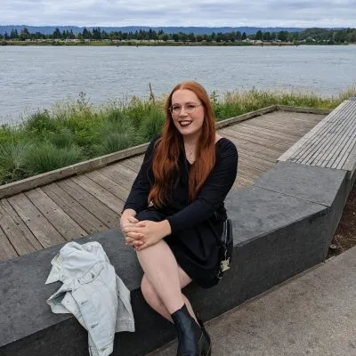 Aspeng Omapang sits next to a body of water in a black dress