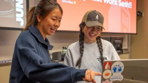 Two AppDev members stand around a computer and smile