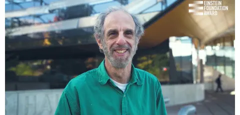 man in green shirt smiling in front of Gates Hall