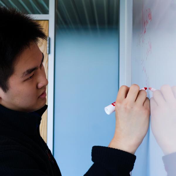 Andrew Kang writes on a white board