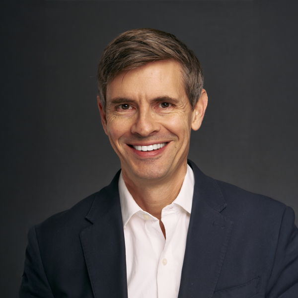 A color photo of a man smiling for a portrait.