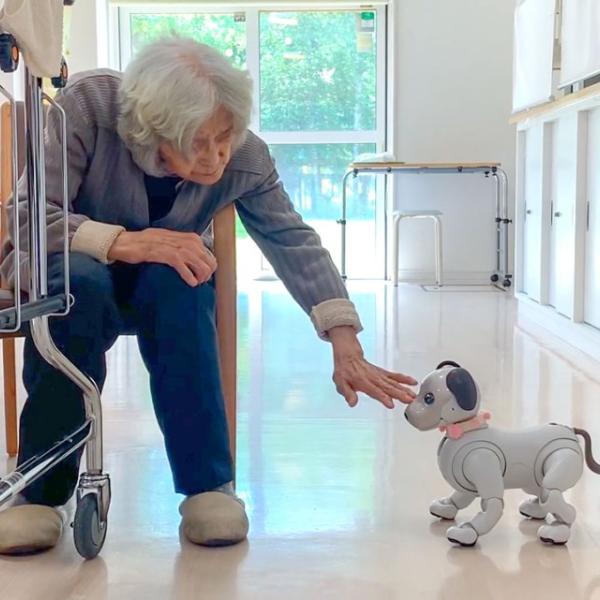 A woman greets a donated Sony aibo social robot at a senior care facility in Japan’s Hokkaido region.