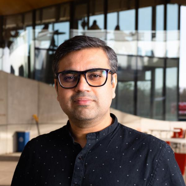  Aditya Vashistha stands and stares at the camera wearing a button-down shirt