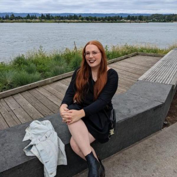 Aspeng Omapang sits next to a body of water in a black dress