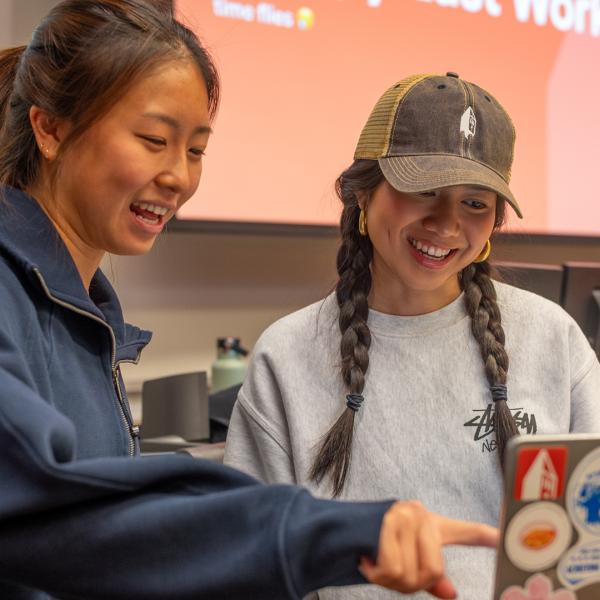 Two AppDev members stand around a computer and smile
