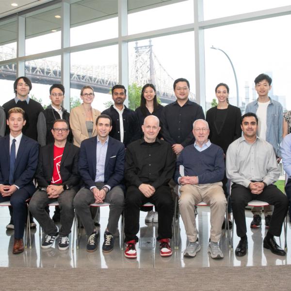 Group of faculty and students lined up for a two-line portrait, flanked by vertical banners.