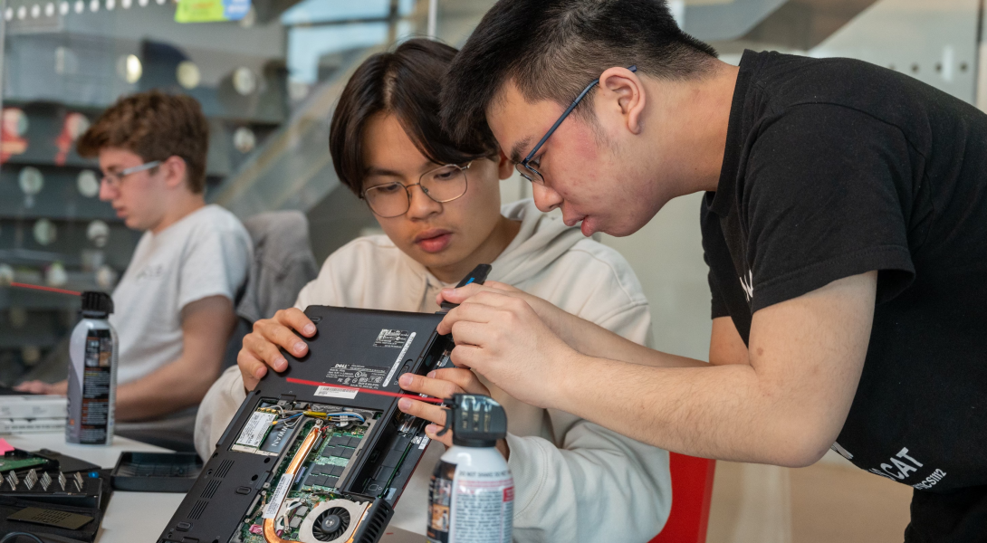 Two students examine a damaged laptop