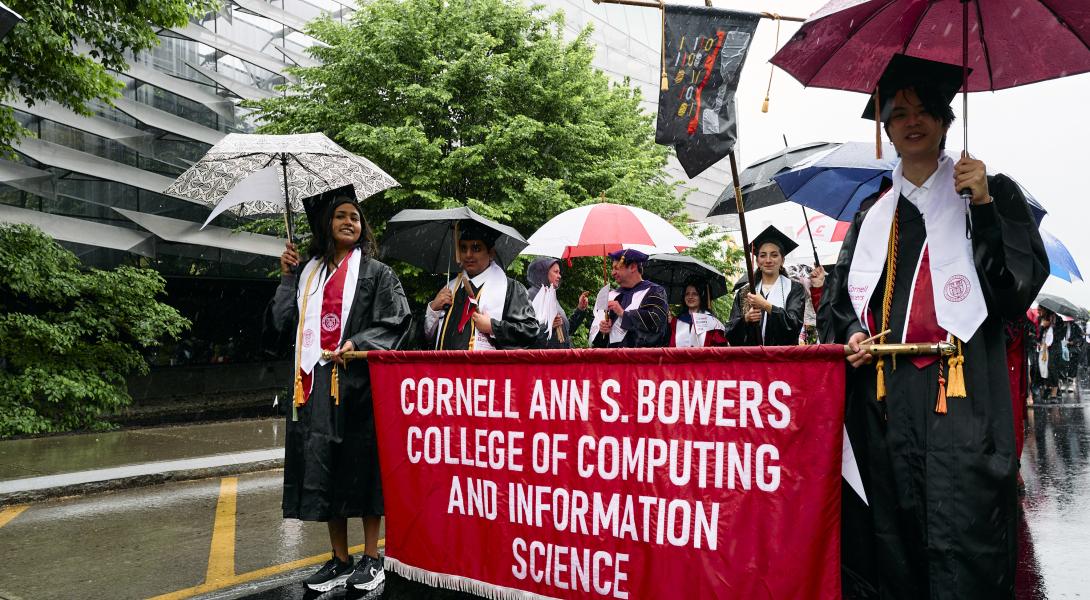 the bowers procession walks behind the red commencement banner