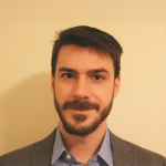 A color photo of Kirk Vanacore in front of a tan background