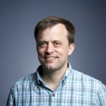 A color photo of Andrew Myers in front of a grey background