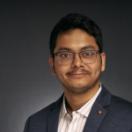 A color photo of a man smiling for a portrait.