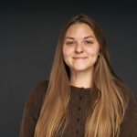 A color photo of a woman smiling for a photo.