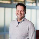 a man with short brown hair wearing a gray sweater