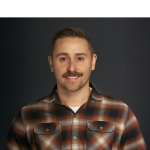 A color photo of a man smiling for a portrait.