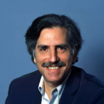 A color photo of a man smiling for a portrait.