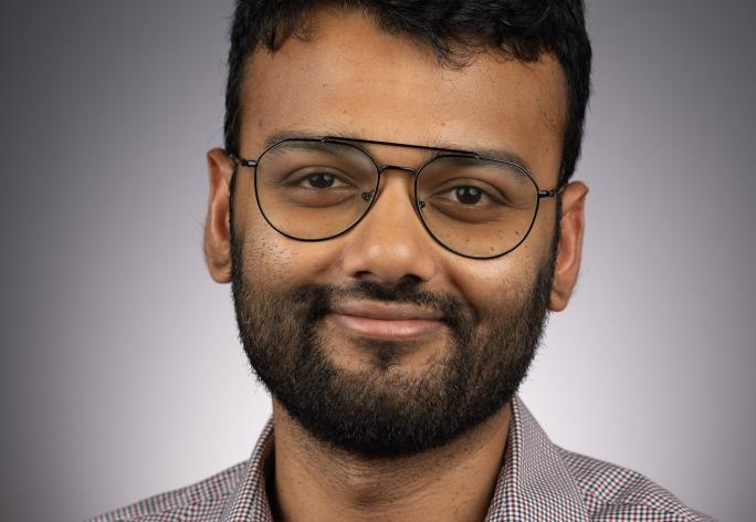 A photo of Eshan Chattopadhyay, a man with dark hair, a beard and glasses in a gray shirt.