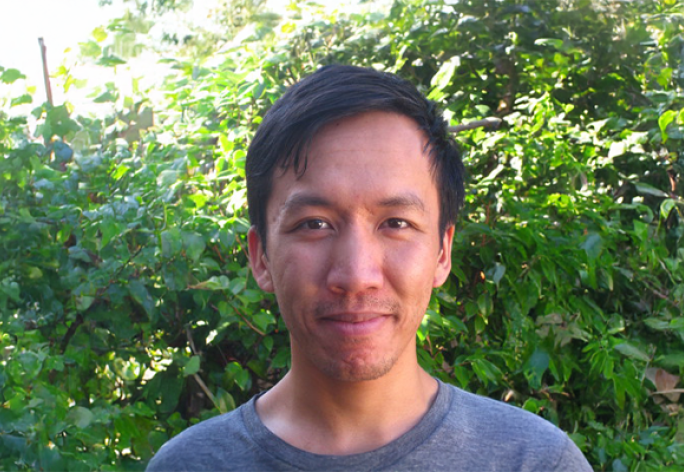 A photo of Justin Hsu, a man with short dark hair in front of a leafy background