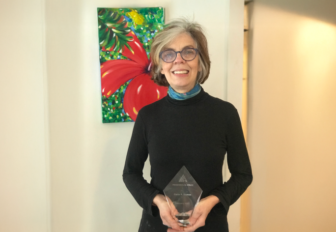 A color photo of a woman holding a glass award.
