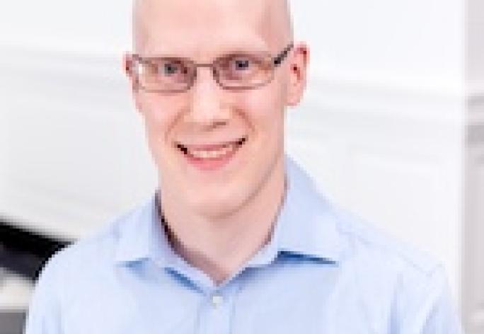 a bald man with glasses wearing a light blue button down shirt