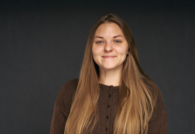 A color photo of a woman smiling for a photo.
