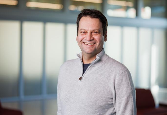 a man with short brown hair wearing a gray sweater