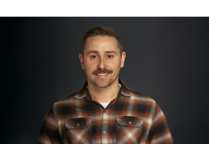 A color photo of a man smiling for a portrait.
