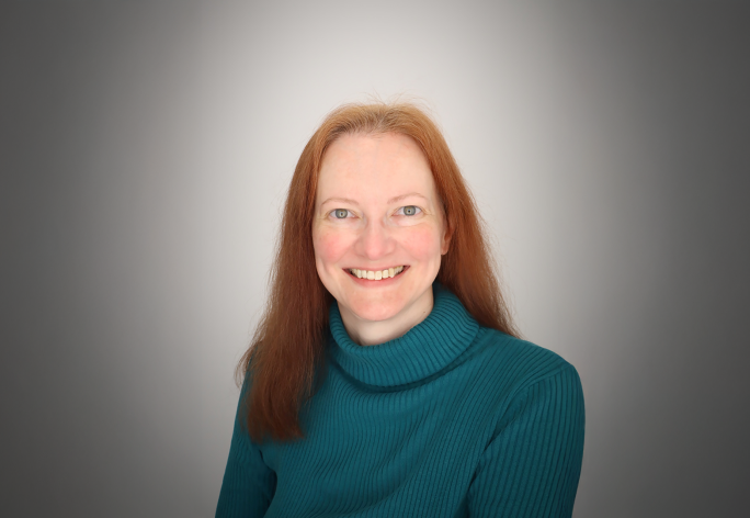 A color photo of a woman smiling for a photo.