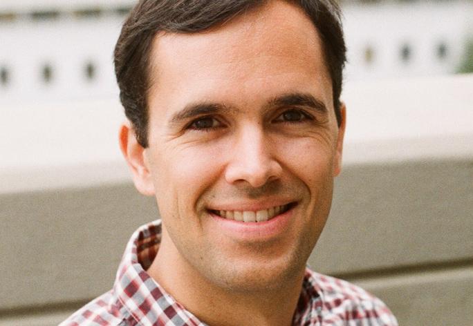 A photo of Anil Damle, a smiling man with brown hair and a red and white checked shirt.