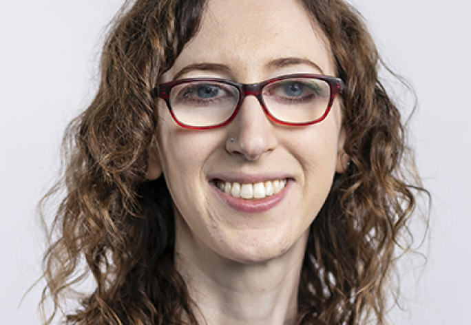 Women with glasses, curly hair, smiling at camera