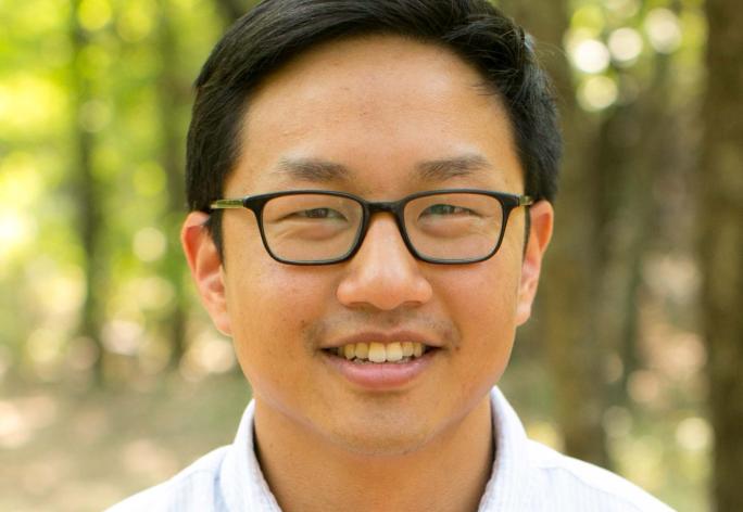 Portrait of a man in white shirt, dark hair and glasses.