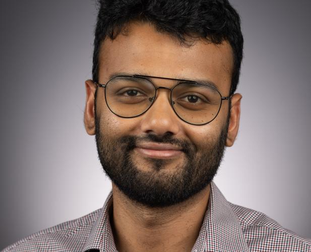 A photo of Eshan Chattopadhyay, a man with dark hair, a beard and glasses in a gray shirt.