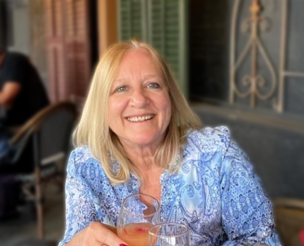 A color photo of Claudia Wojcinski sitting at an outdoor patio with a drink