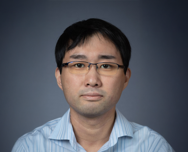 A color photo of asian man looking at camera, wearing glasses