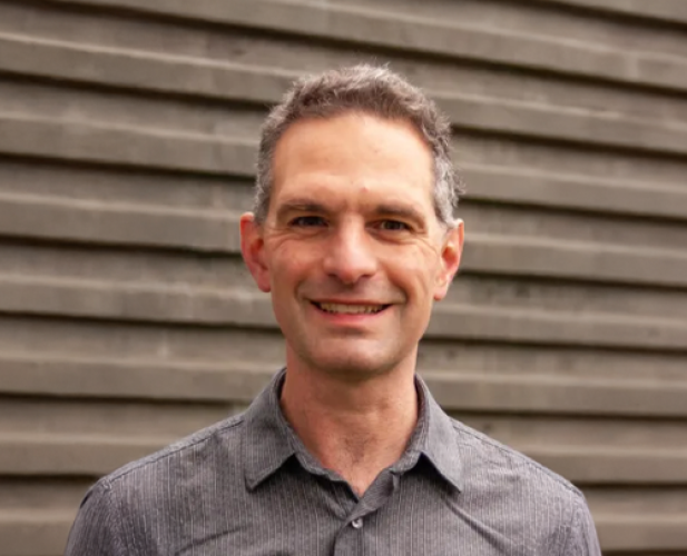 A photo of Stephen Marschner, a smiling man with short gray hair and a gray shirt, in front of a gray background