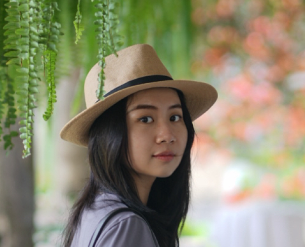 A color photo of a woman with dark hair wearing a hat.
