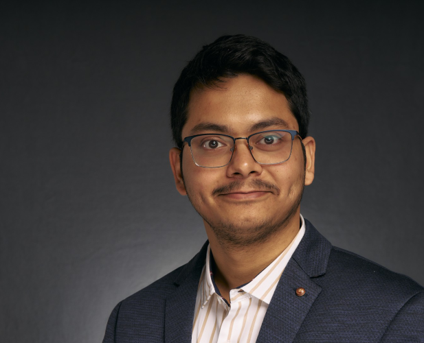 A color photo of a man smiling for a portrait.